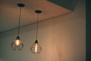 Stylish geometric pendant light fixtures casting warm light in a minimalistic indoor setting.
